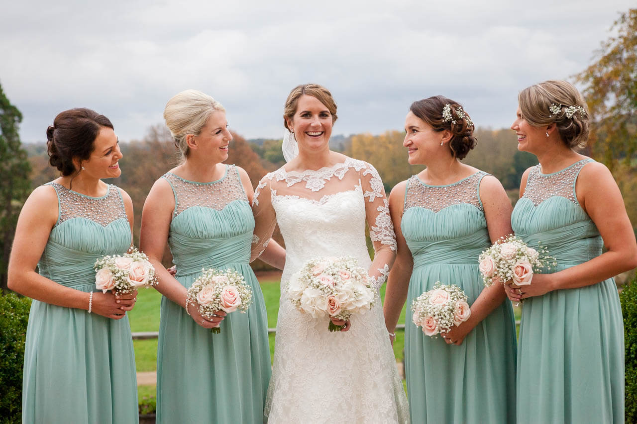 bride smiling at camera with bridesmaids all looking at her