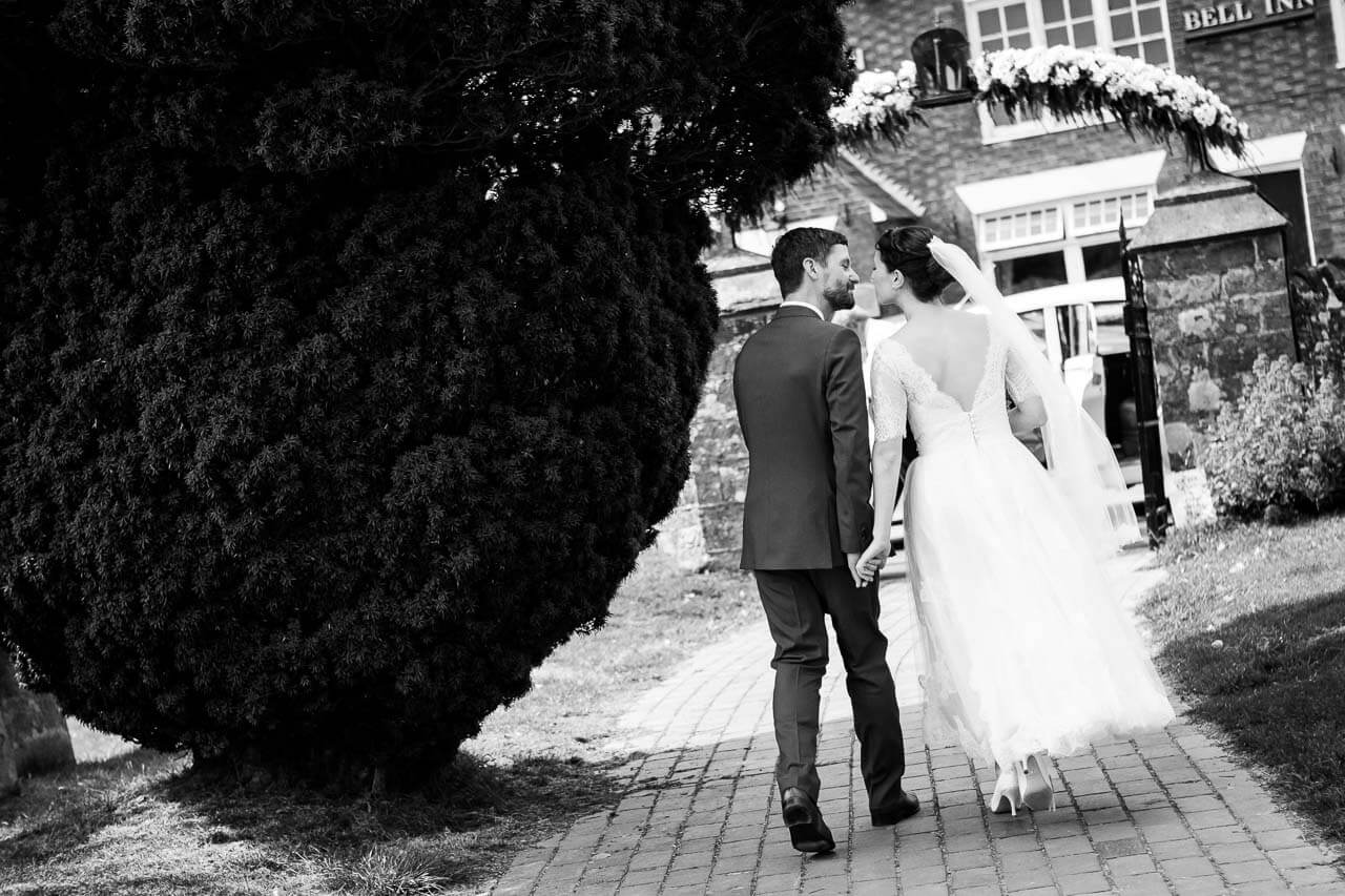 bride and groom walk away from the church looking at each other