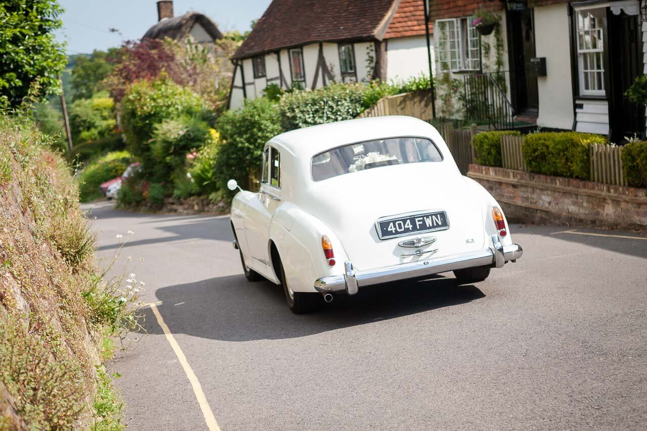 white wedding drives off through Burwash village