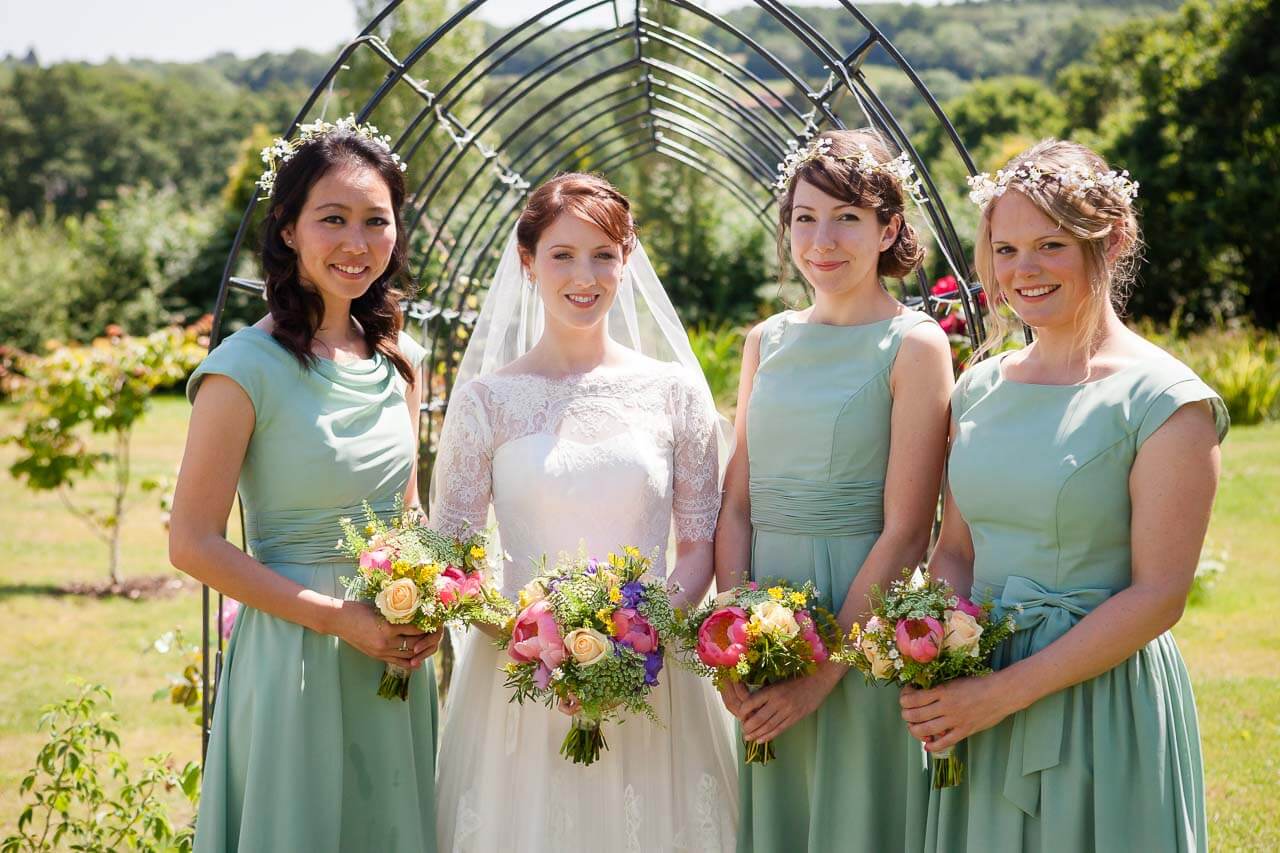bride with her bridesmaids all looking at the camera smiling