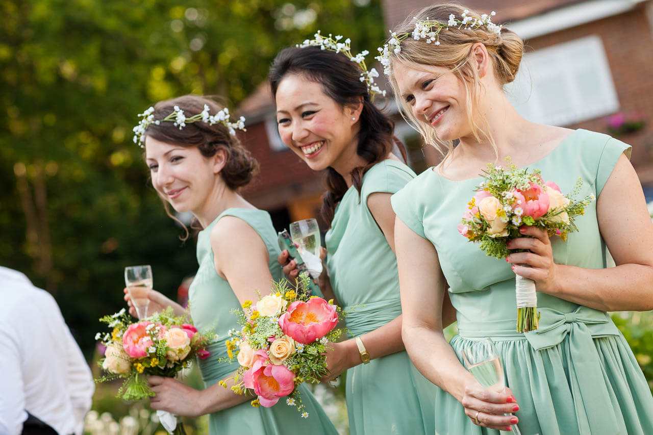 three bridesmaids smiling and laughing at guests