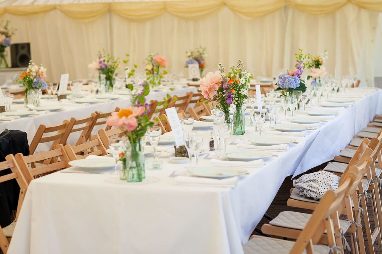 close up of beautifully decorated tables with flowers in glass jars