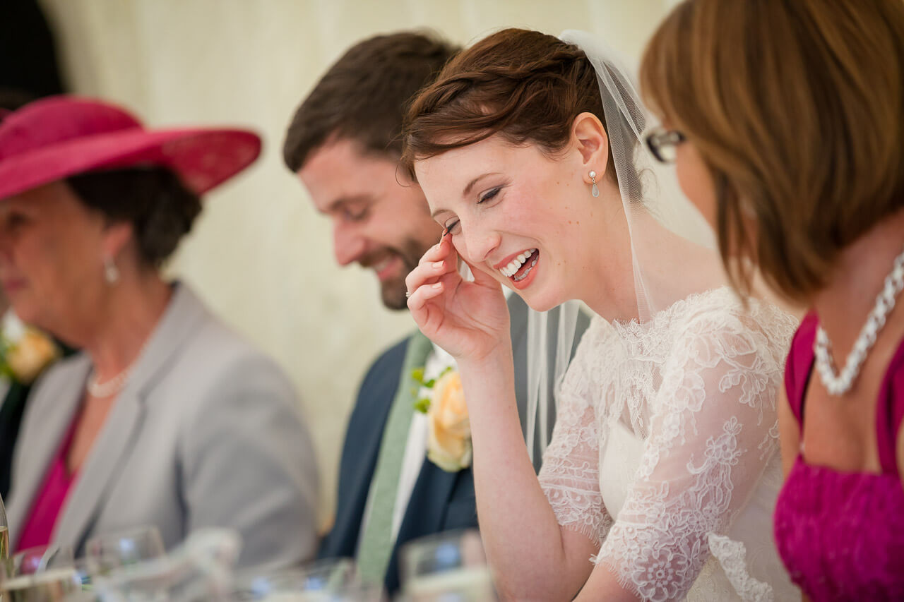 bride wipes away a tear after laughing so much during speech