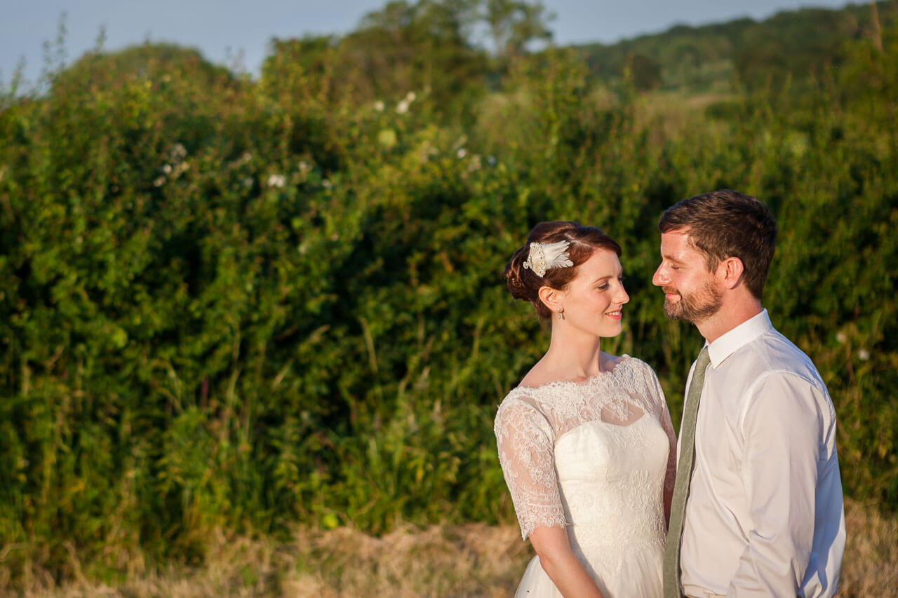 golden hour photo of bride and groom looking at each other holding hands