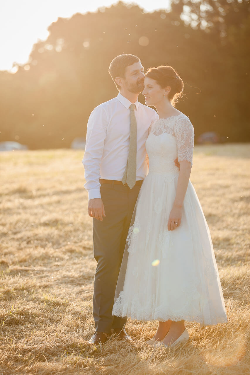 groom kisses forehead of bride during golden hour