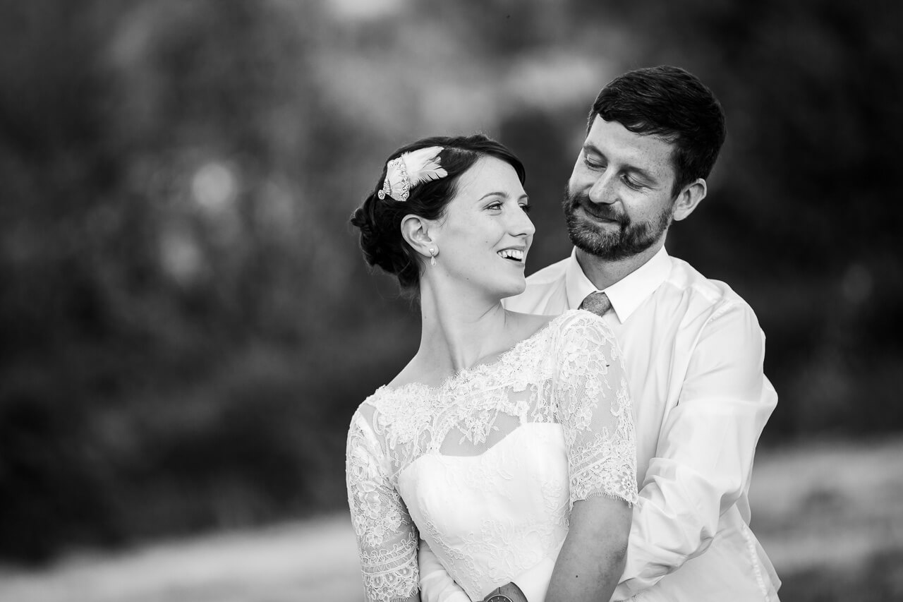 bride looks up to groom with his arms around her waist