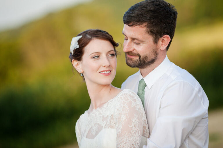 groom looks on bride's face as she turns and looks out to the field