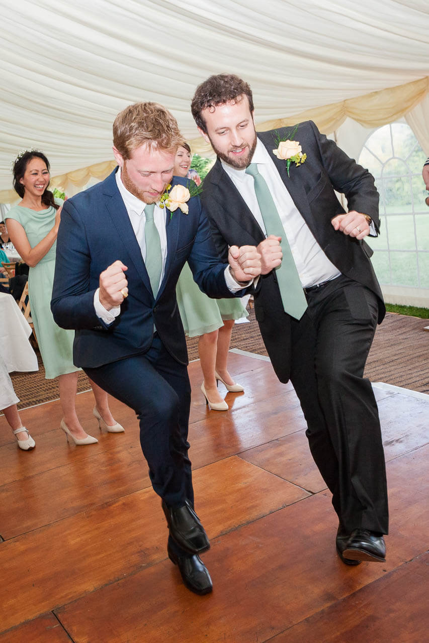 two guys linking arms dancing merrily to live band