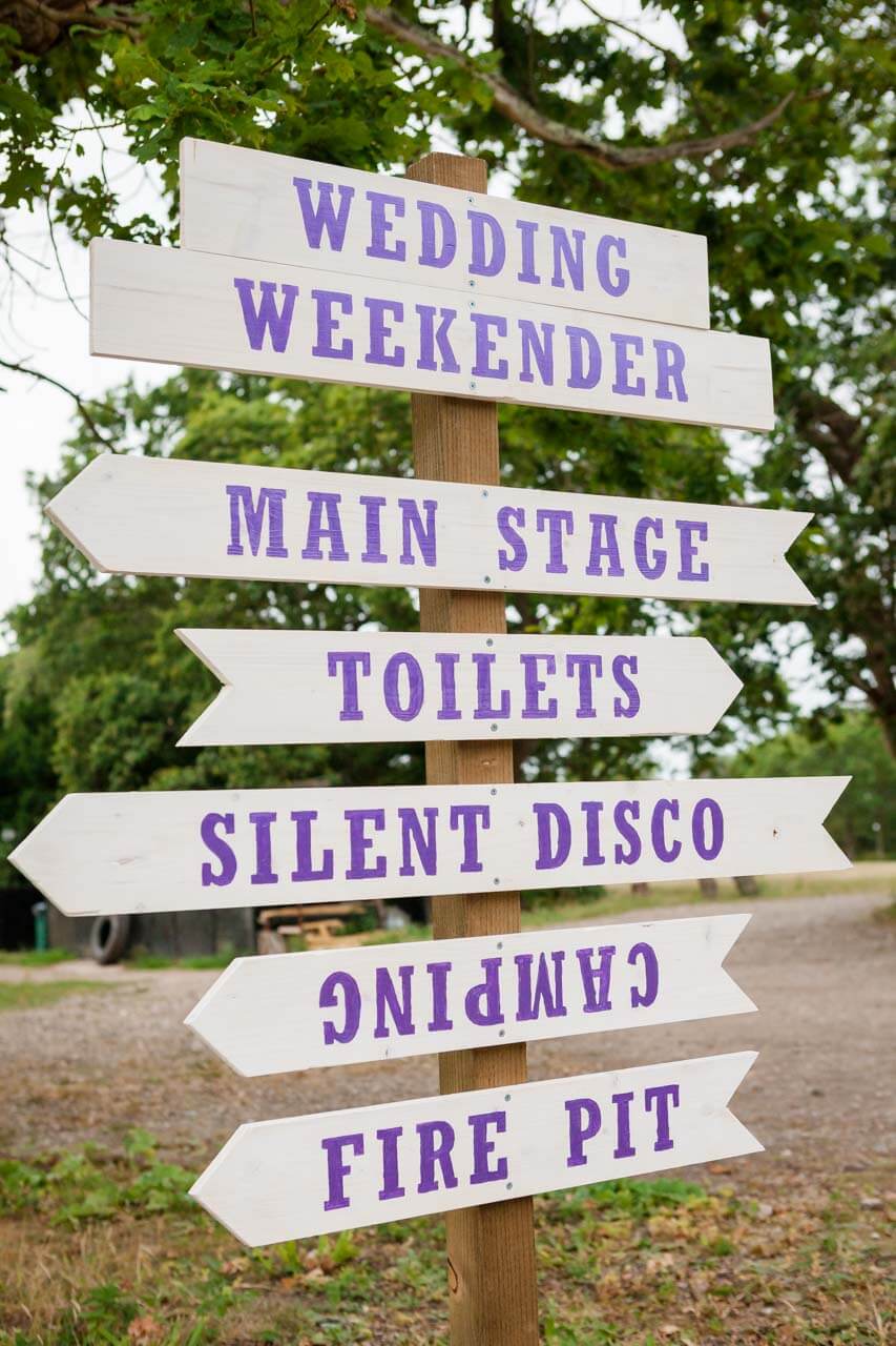 white wooden sign post with purple lettering of wedding directions