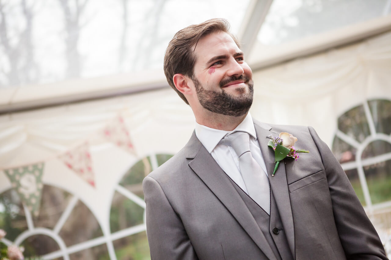 groom smiling as he watches bride walking down the aisle