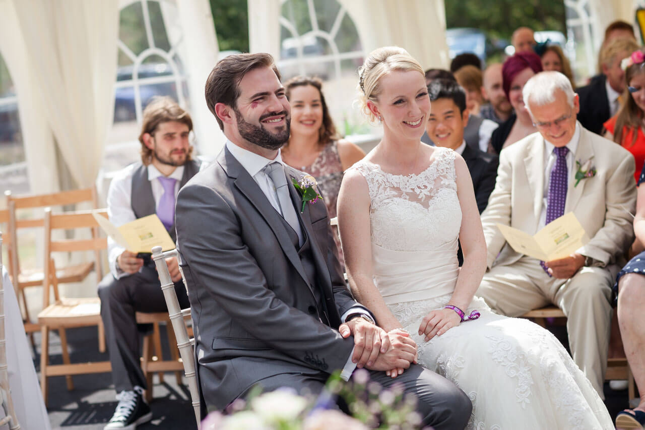 bride and groom holding hands listening to reading during ceremony