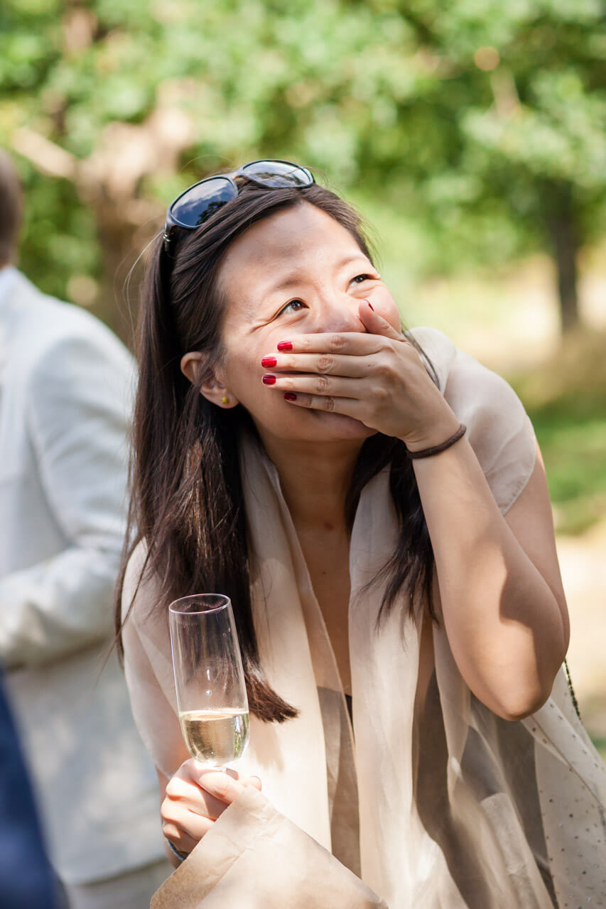guest with hands over mouth laughing during reception drinks
