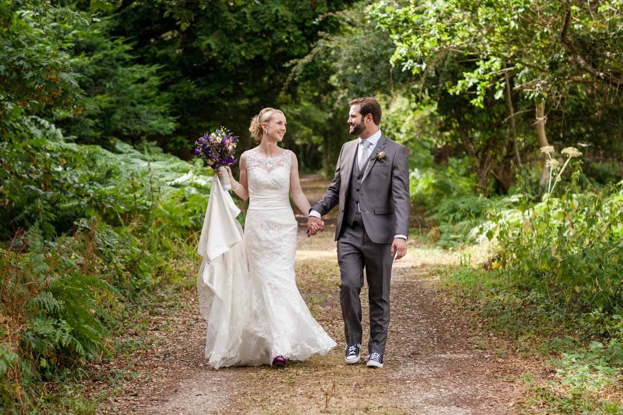 bride and groom walking towards each other in woody tree lined lane