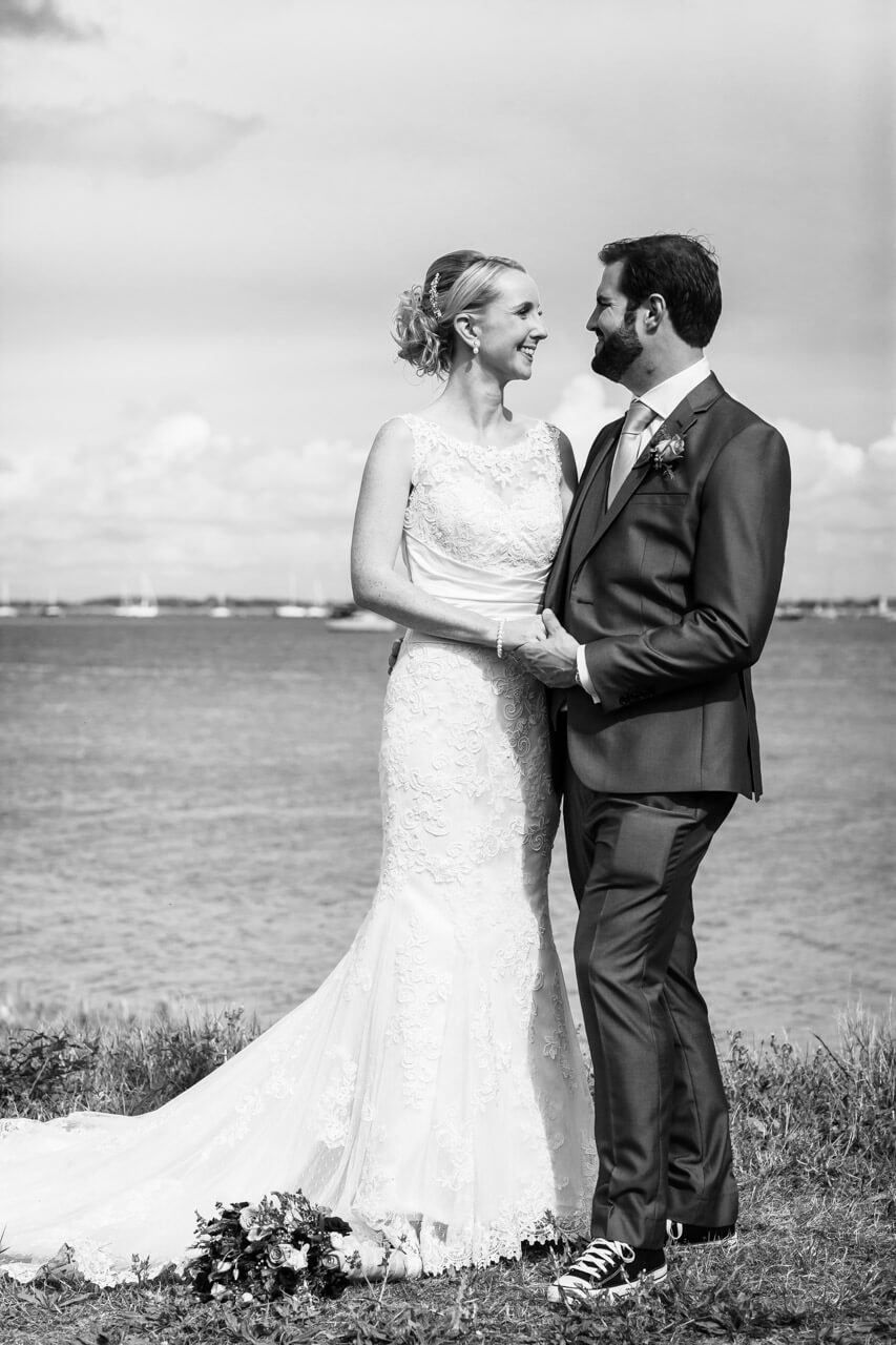 bride and groom look to each other with sea in background