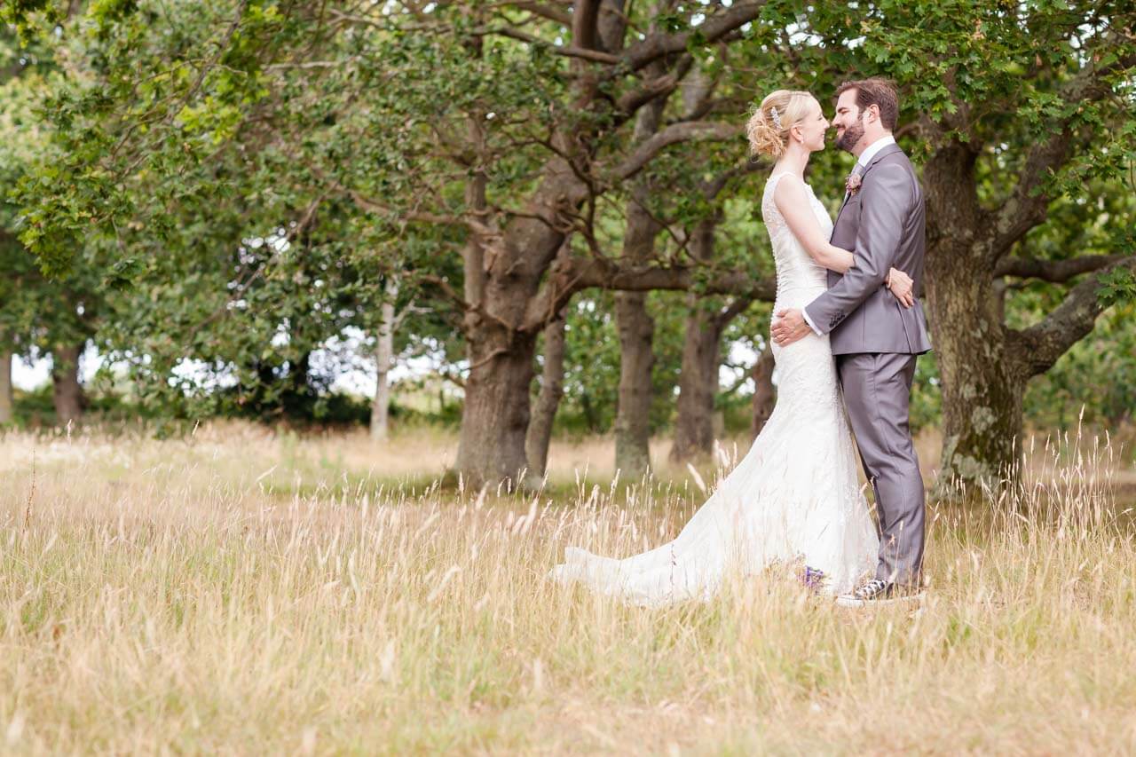 bride and groom holding each other close in long grassed field