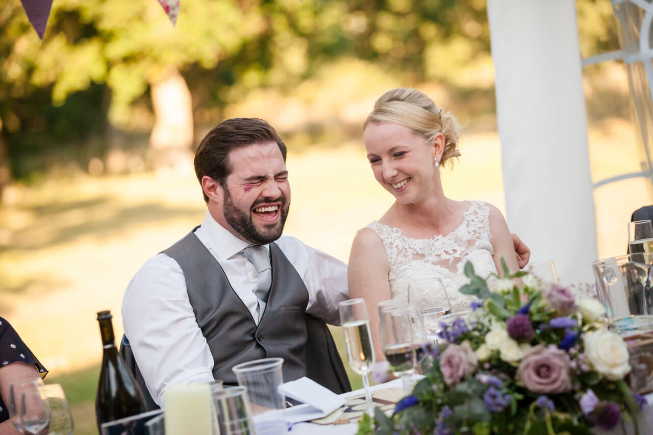 bride looks to groom laughing during speech