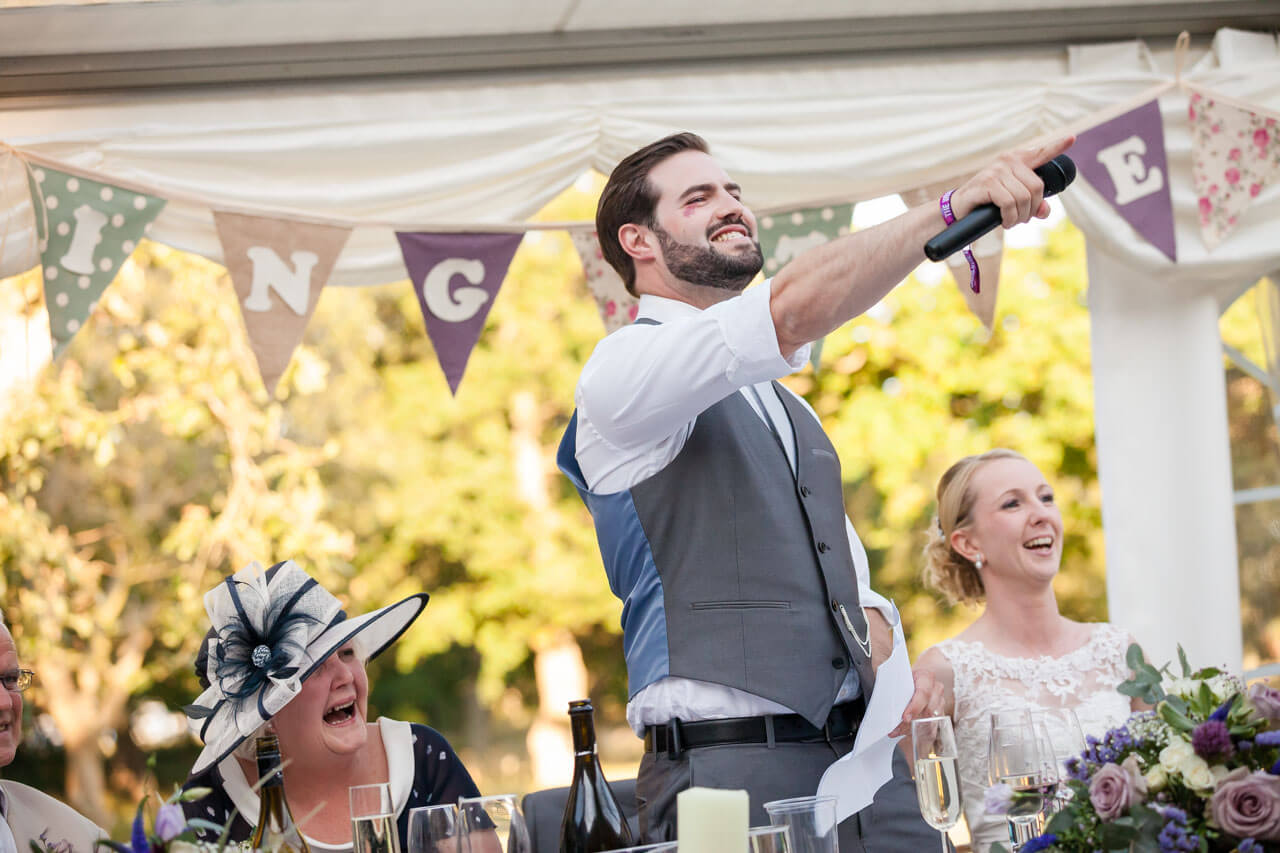 groom pointing to someone in the crowd while doing speech