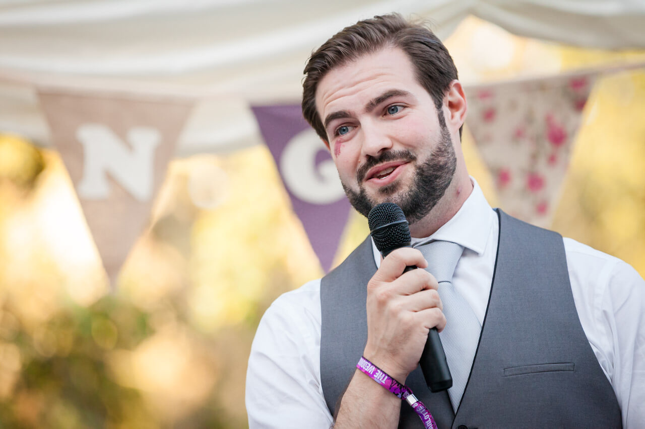 groom holding microphone while doing speech
