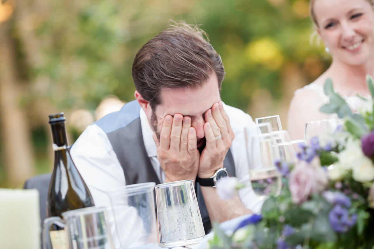 groom with head in hands while listening to speeches