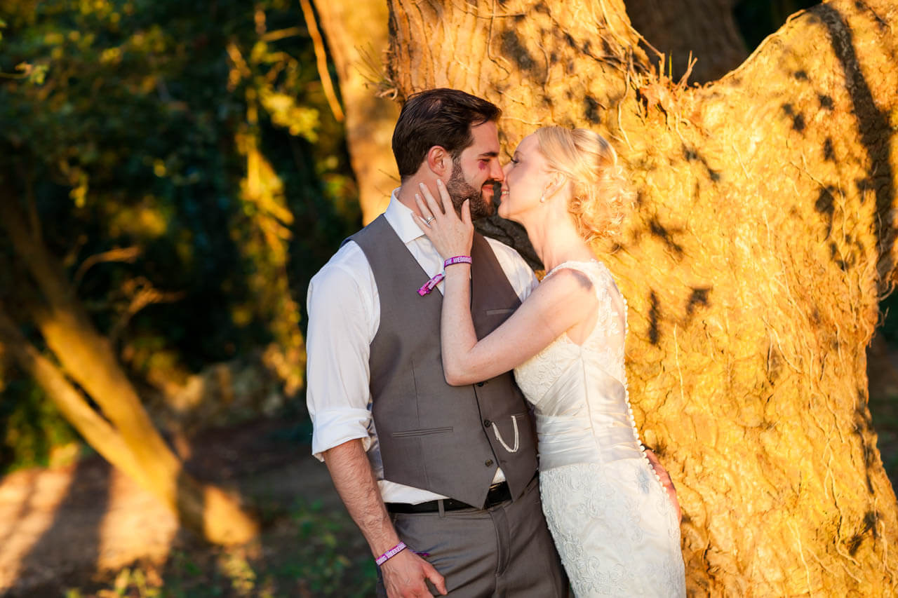 bride cups groom's face with her hand drawing him in for a kiss