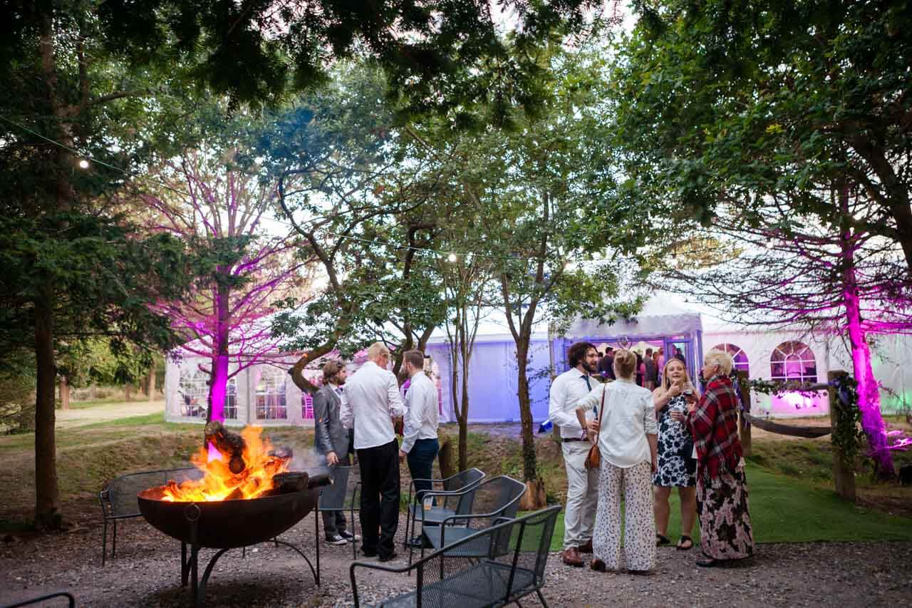 shot of guests mingling outside with fire pit lit