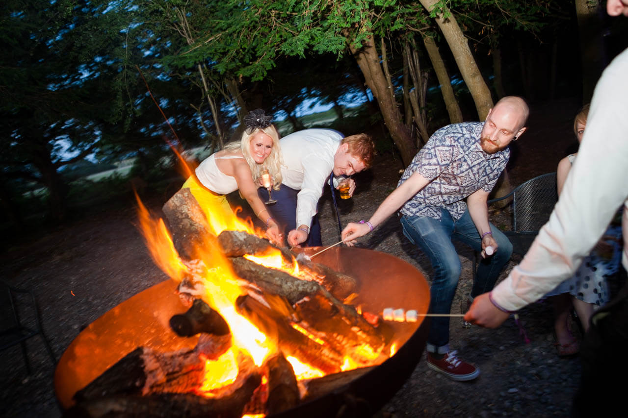 guests around fire pit toasting marshmallows