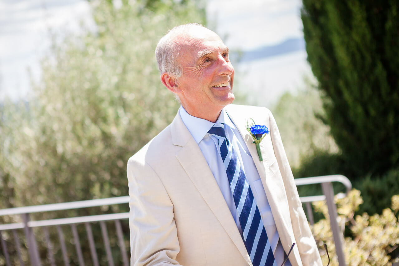 father of bride looking up to bride in villa window