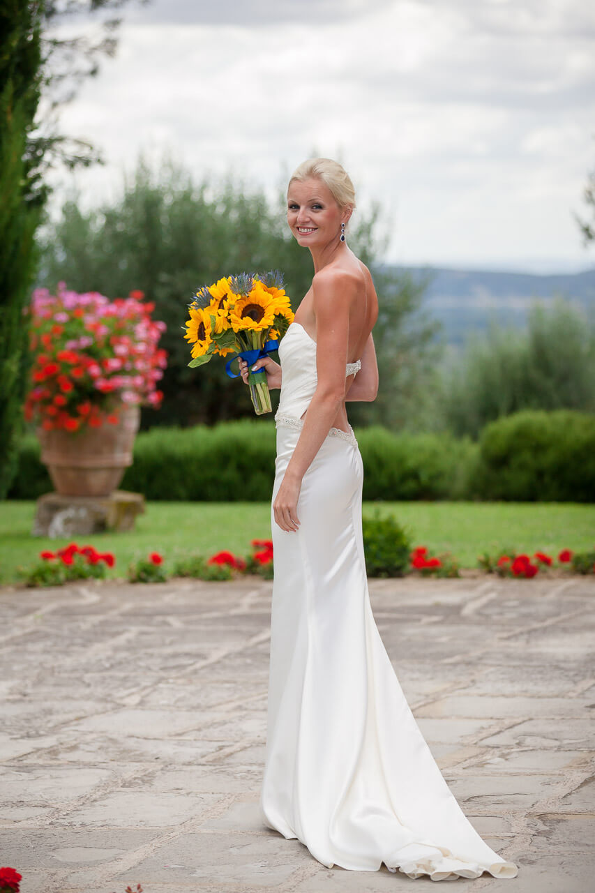 bride looks back at camera holding her sunflower bouquet