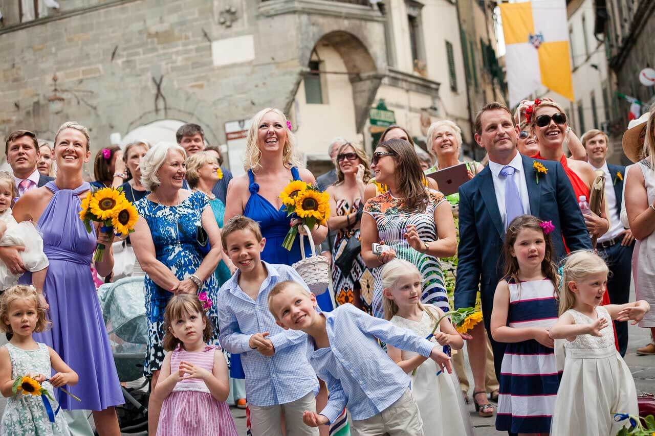 group of guests looking up at town hall balcony cheering at newlyweds