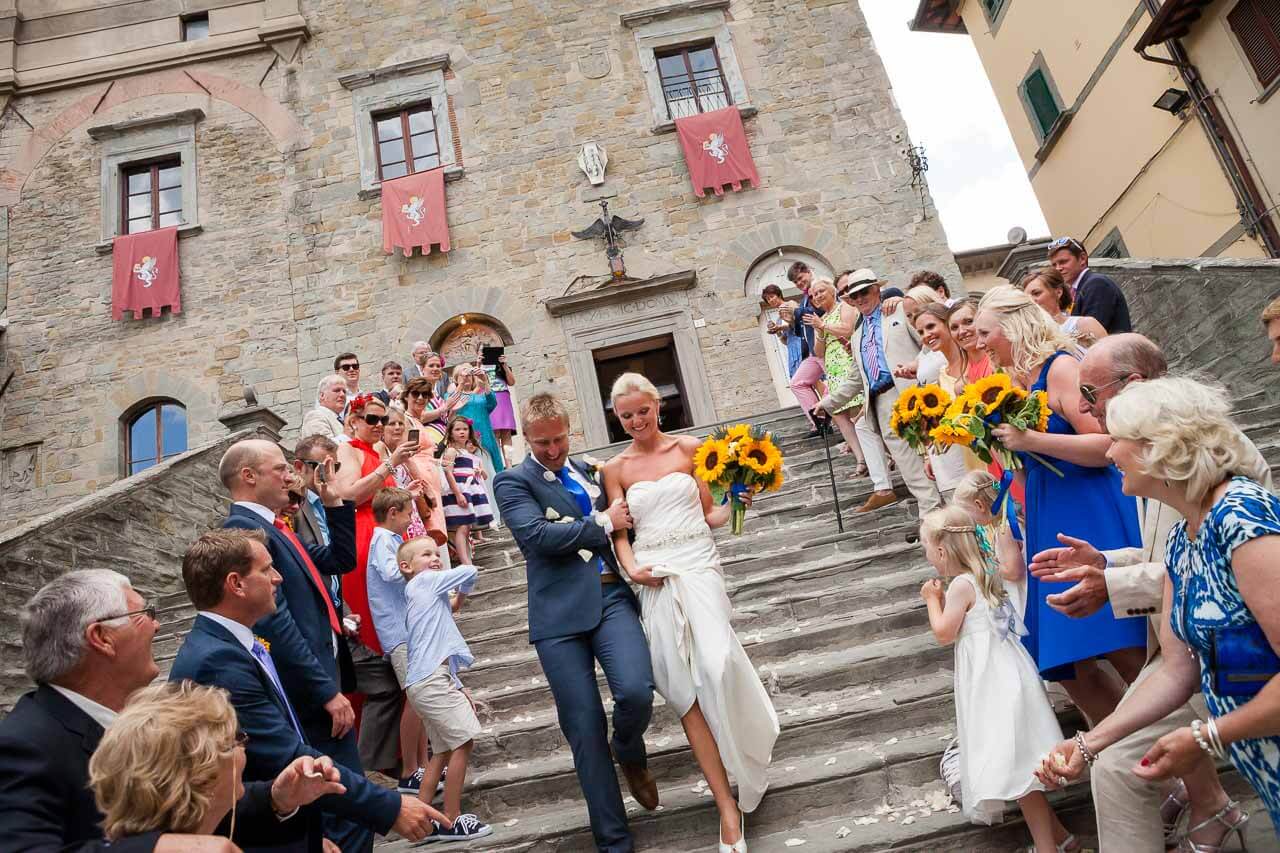 bride and groom walking down steps of town hall with confetti thrown at them