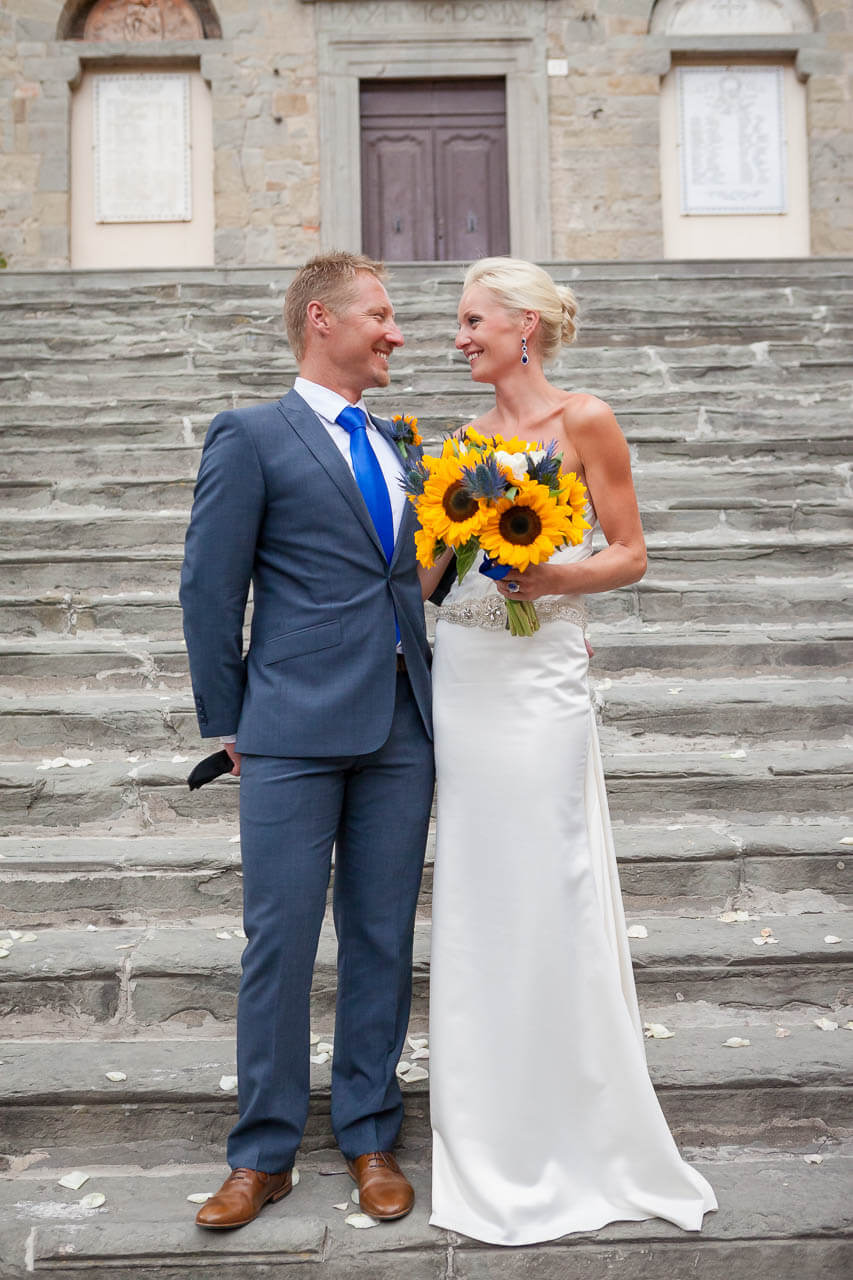 bride and groom smile at each other on steps of town hall