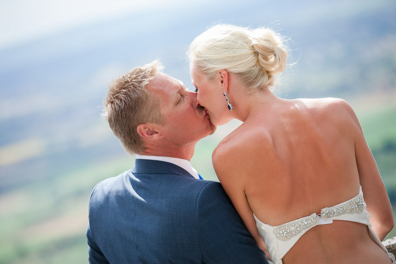 bride and groom kiss with camera behind their backs
