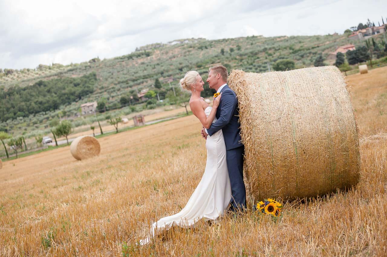 couple leaning against hay bale looking at each other