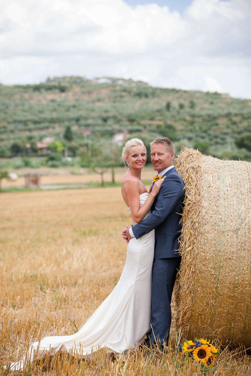 couple looking at camera with hay bale behind them