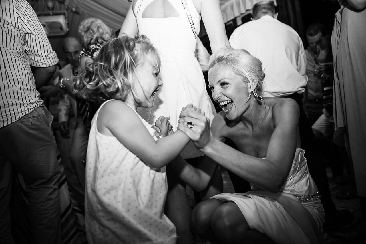 bride crouched down dancing with flower girl