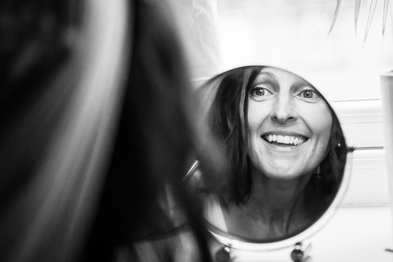 bride looking in mirror doing make up