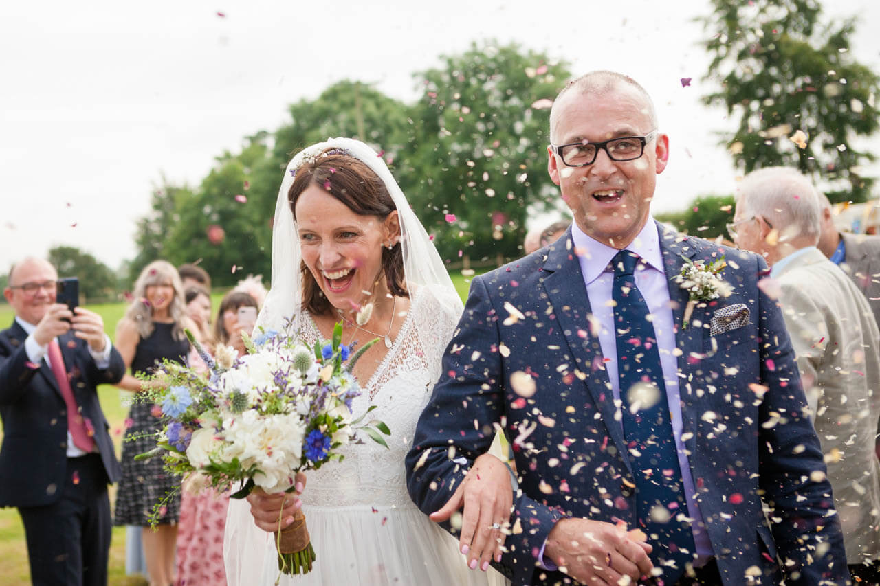 bride and groom laughing walking into confetti