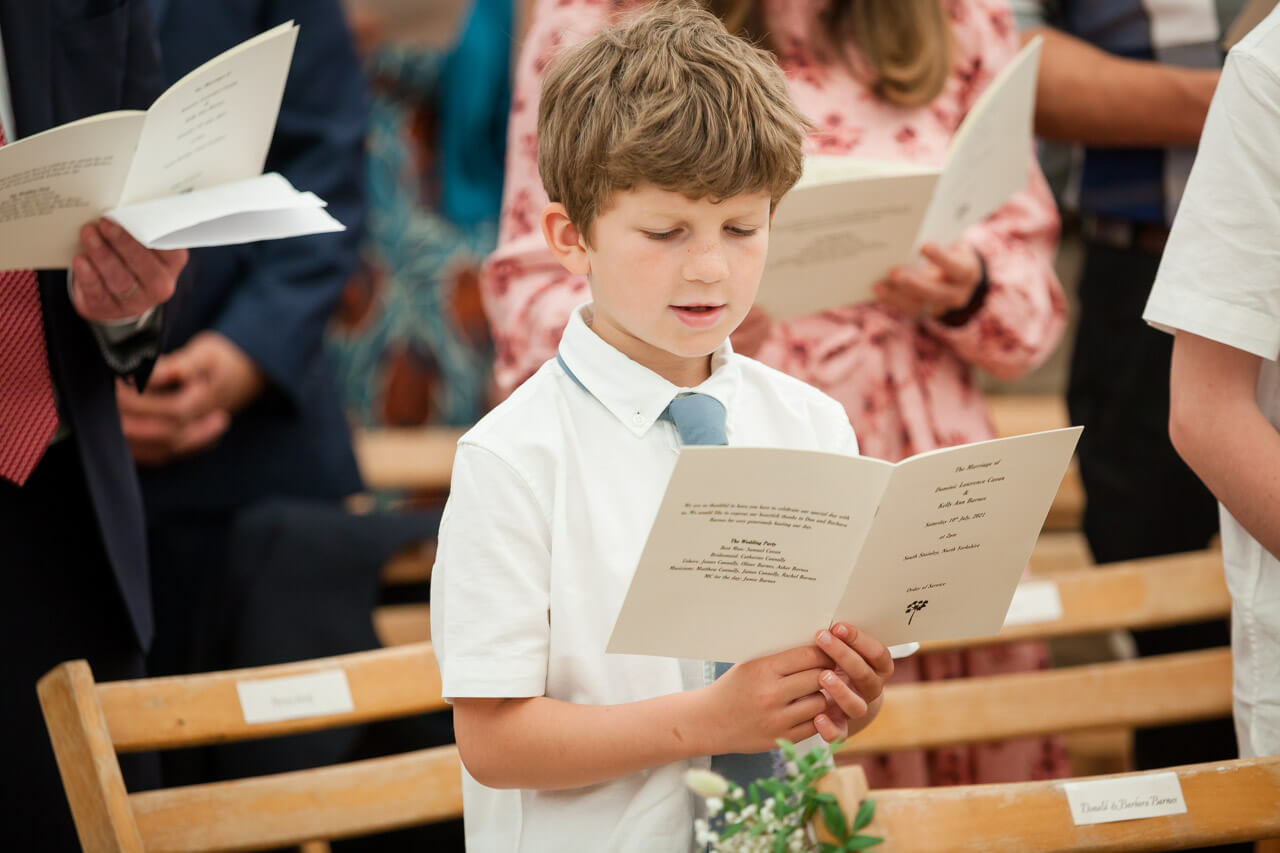 page boy singing holding the order of service