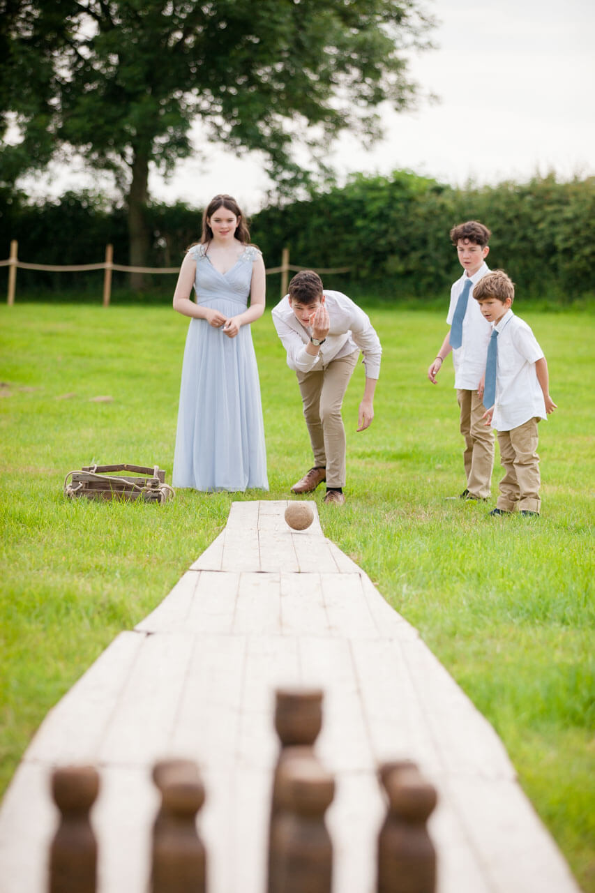 boy rolling ball towards skittles