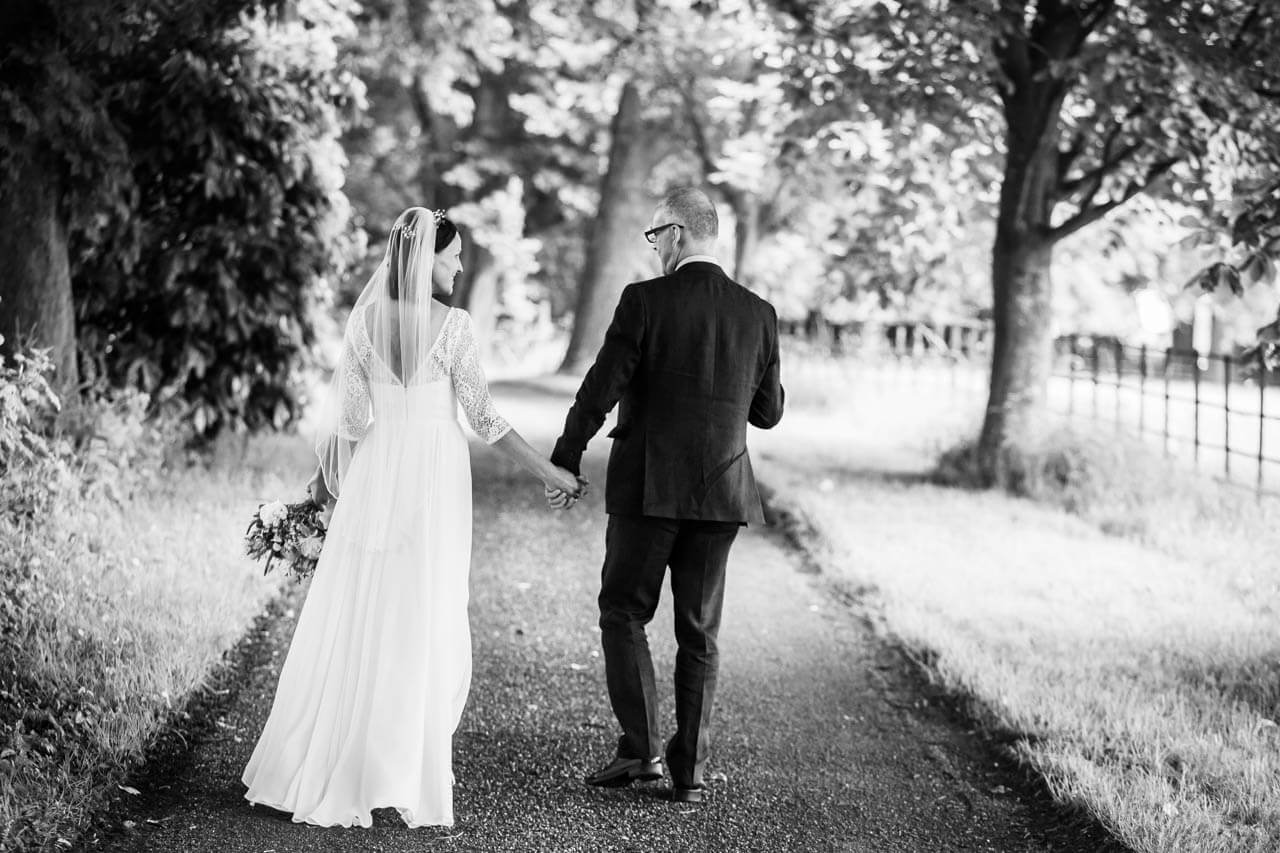 bride and groom walking away from camera down a country lane