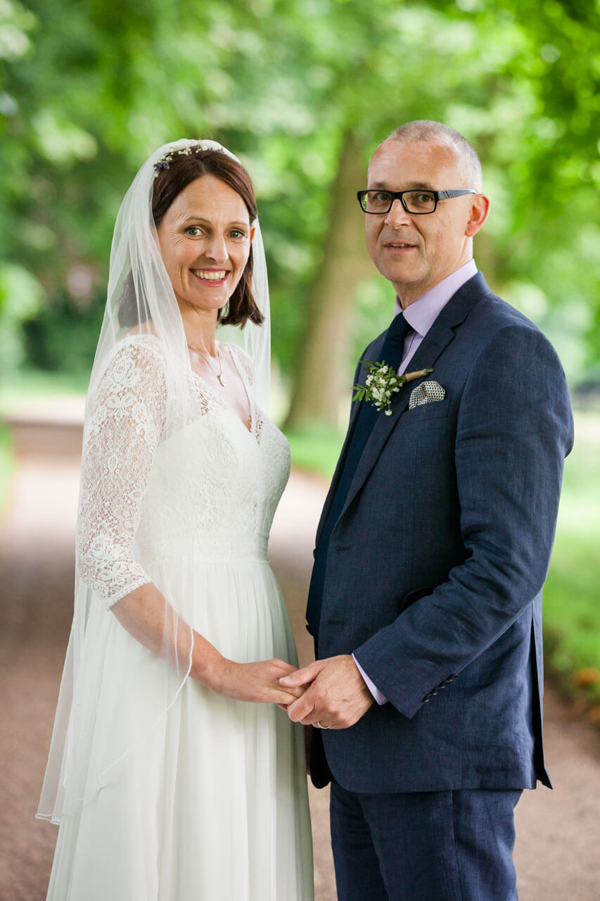 bride and groom looking at camera with green trees in background