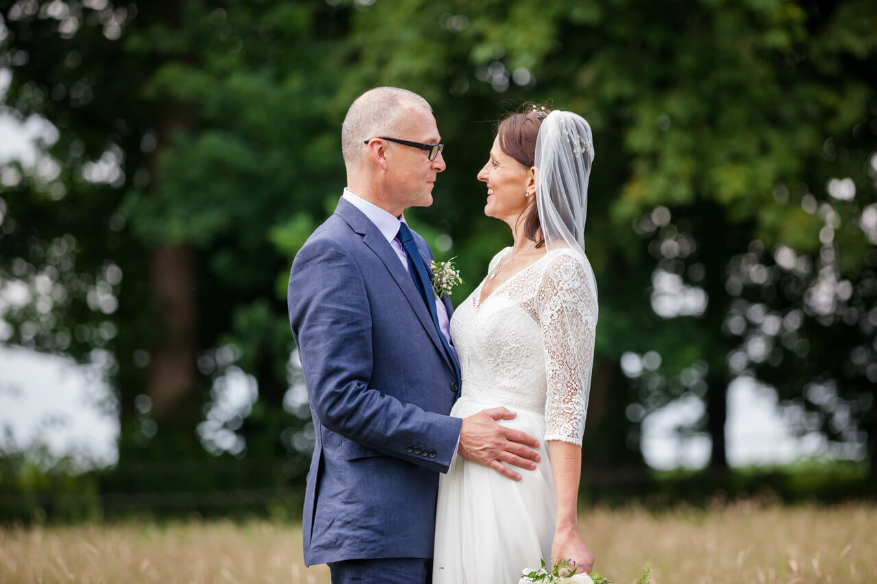 bride and groom in field with groom round bride's waist