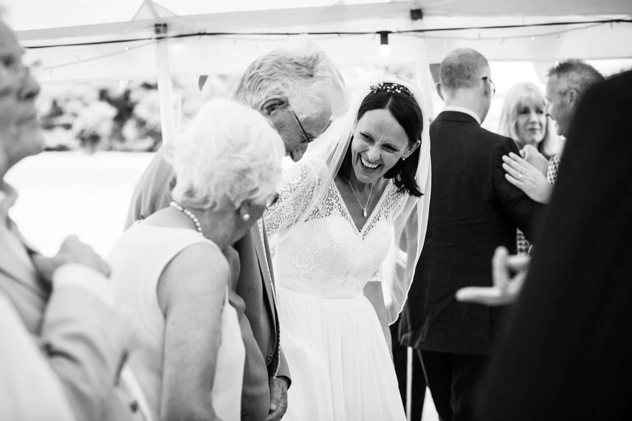bride laughing with her mother in wedding line up
