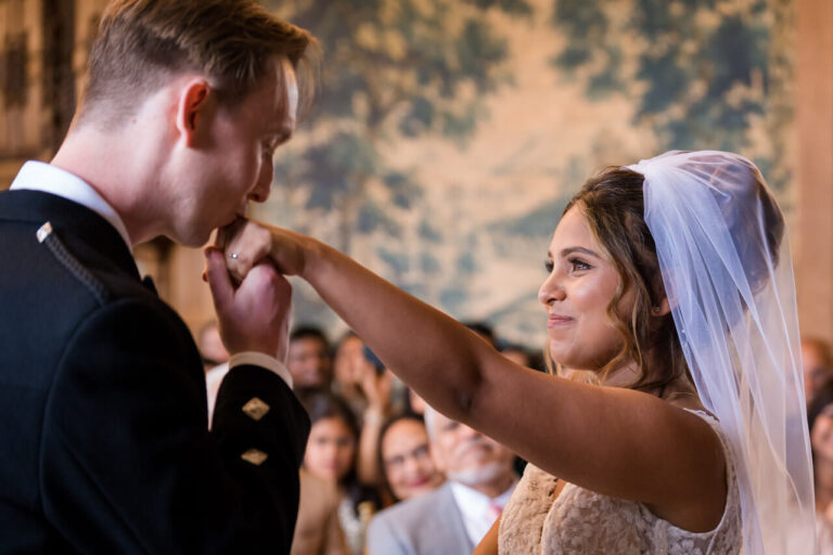 Tearful bride holds hand up to groom to kiss