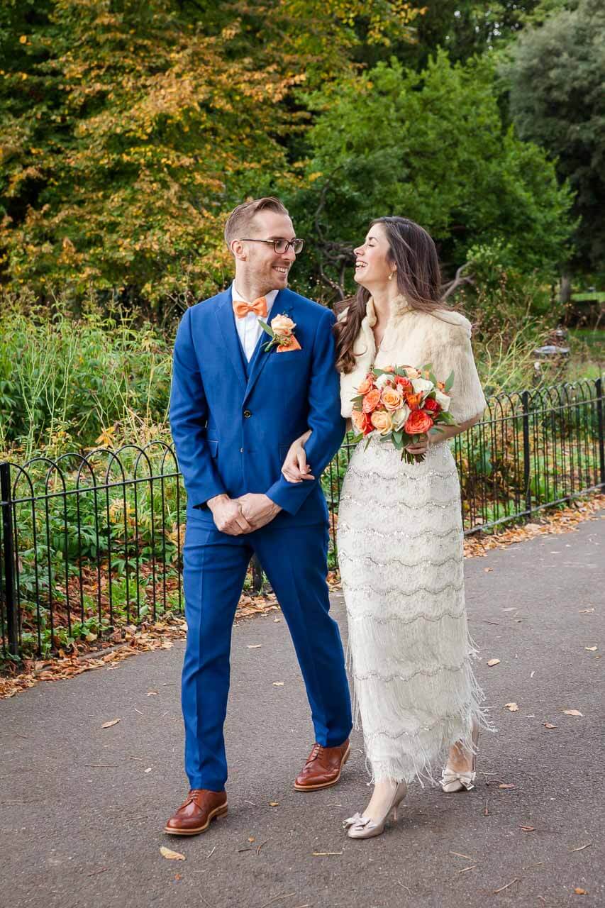 bride and groom linking arm in arm walking through park
