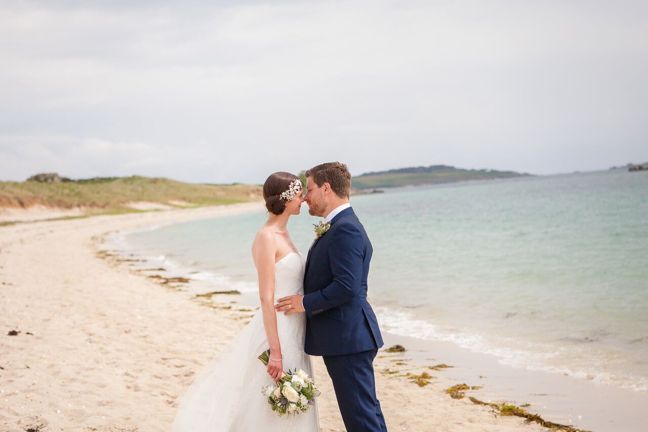 bride and groom embrace on beach