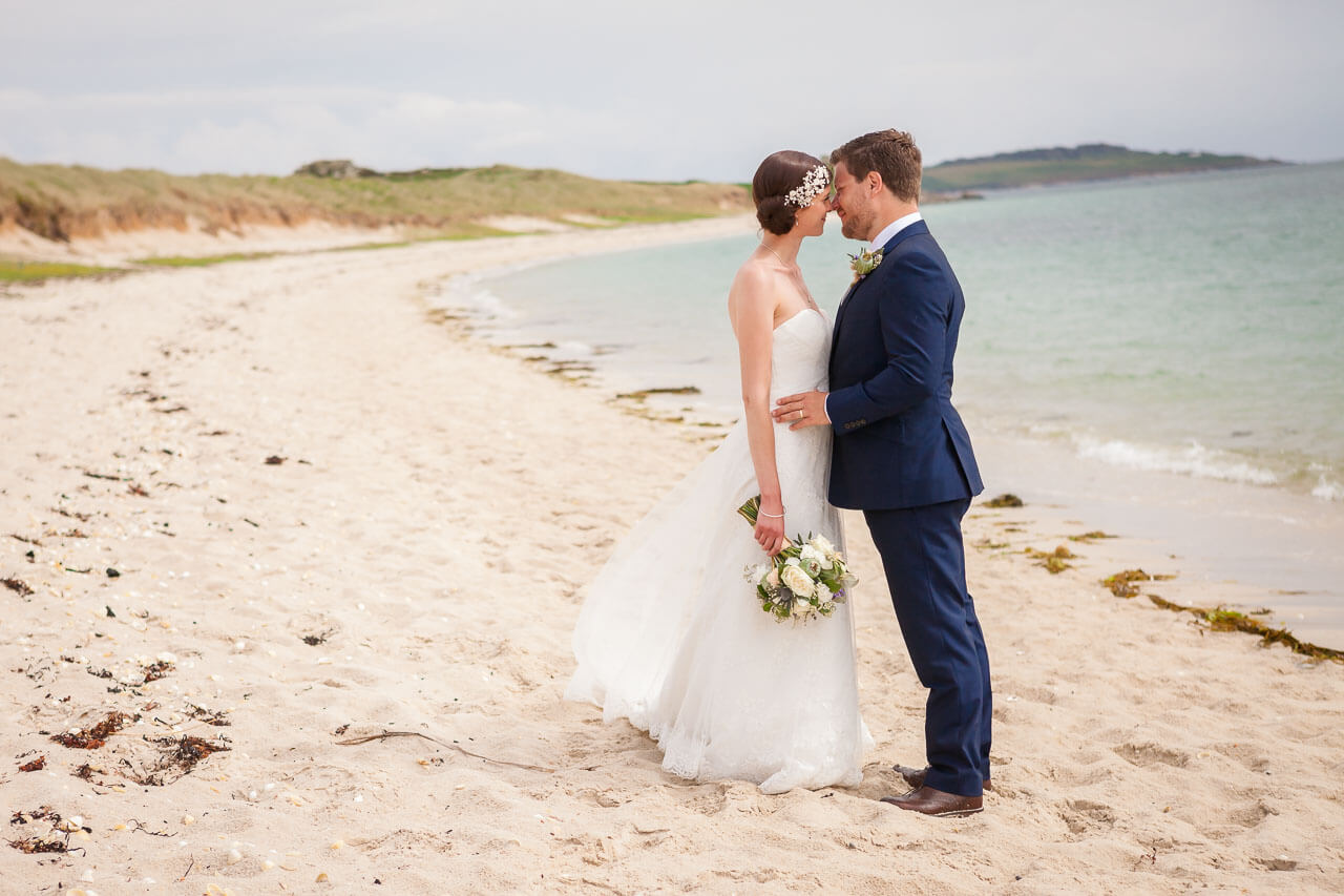 bride and groom standing opposite each other on beach 