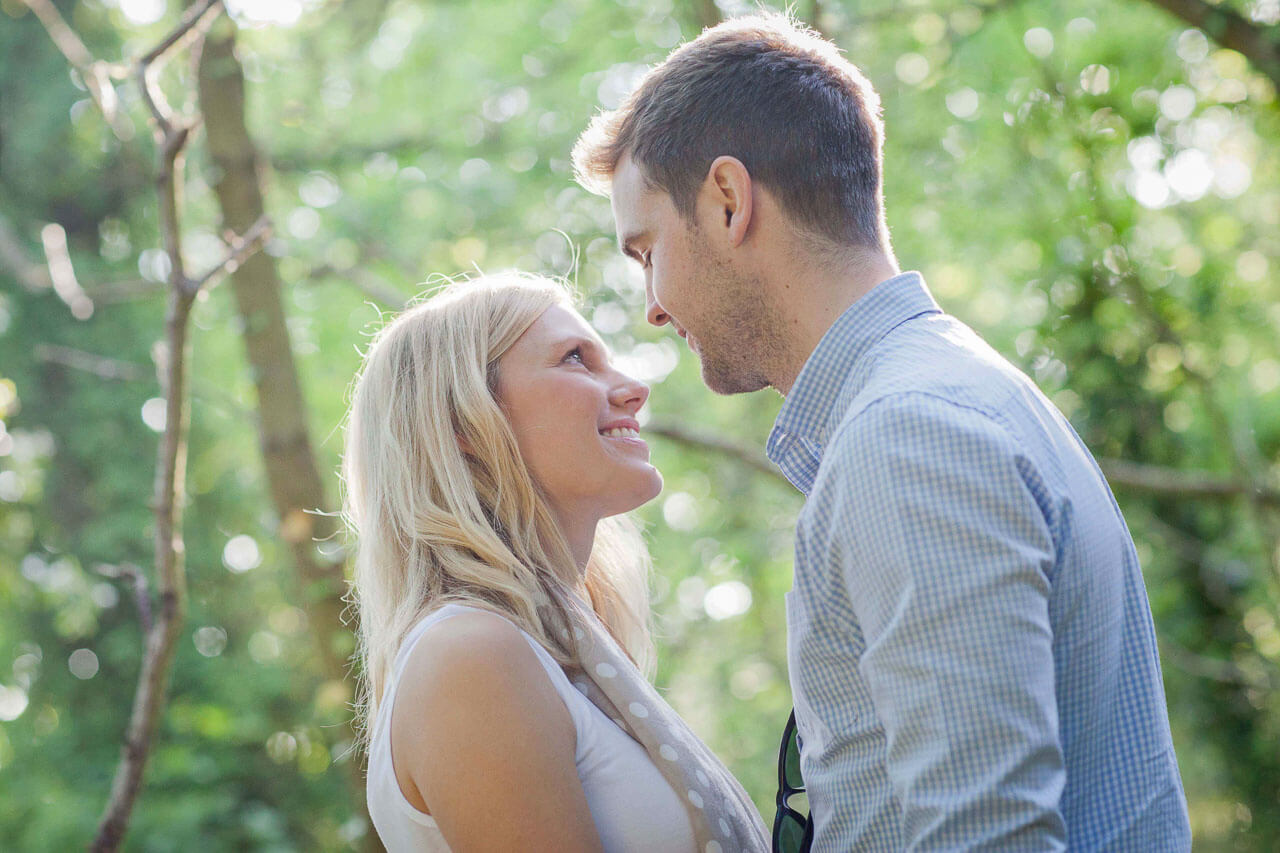 couple looking into each others eyes with woodland behind them