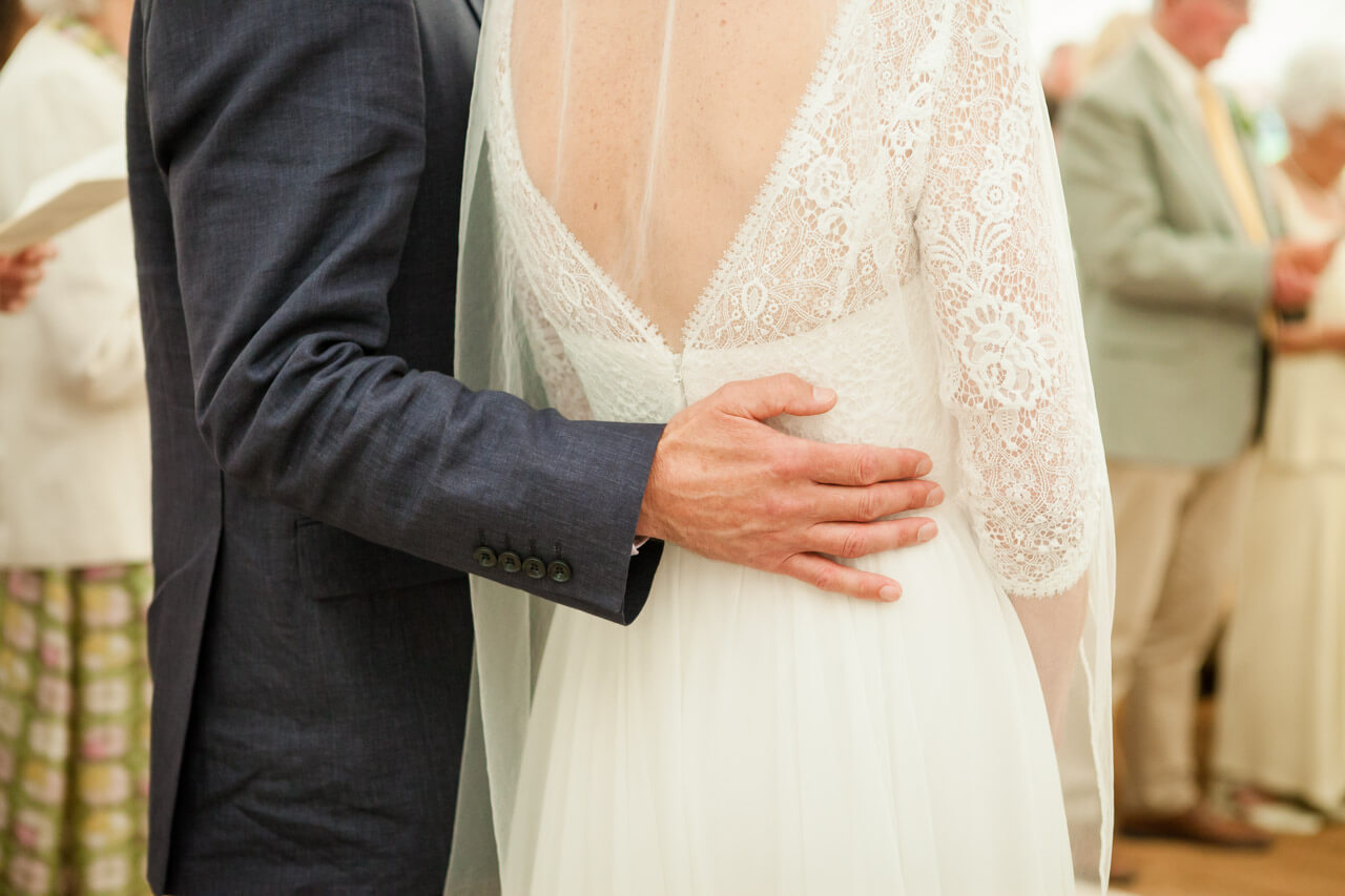 groom puts hand round brides back