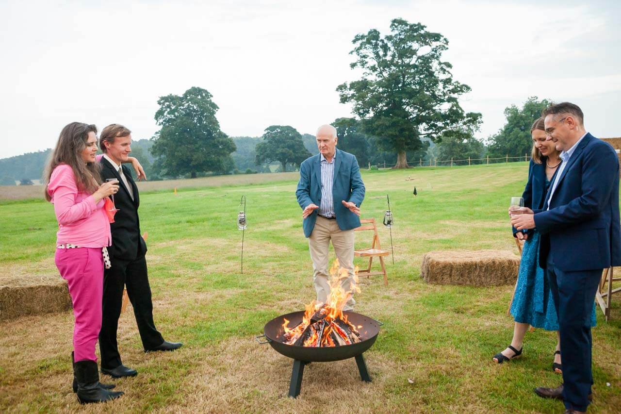 guests warm themselves by fire pit